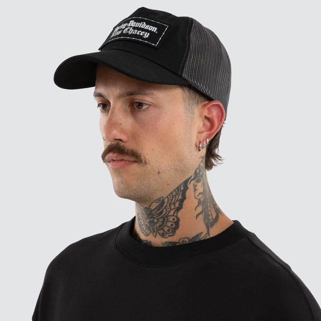 Model wears Hog Trucker Cap Charcoal/Black Caps Black – image 2