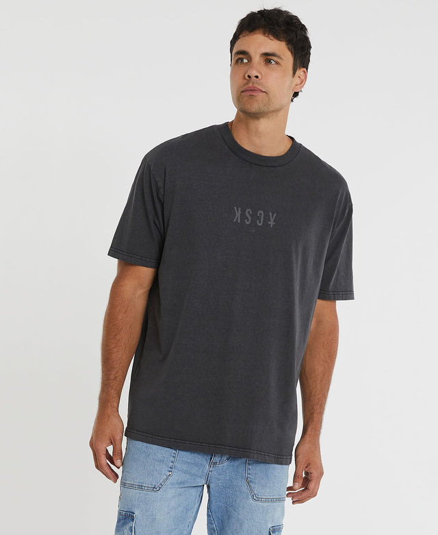 Man wearing a black box fit t-shirt with ribbed collar neckline by Kiss Chacey, featuring a light grey inverted brand logo text.
