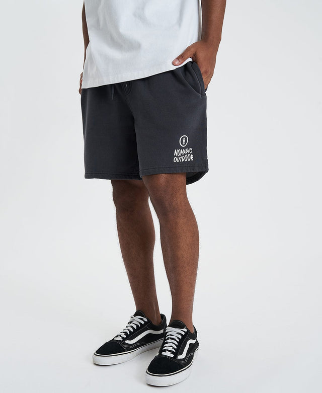 Man showcases Nomadic's black shorts with classic logo on side